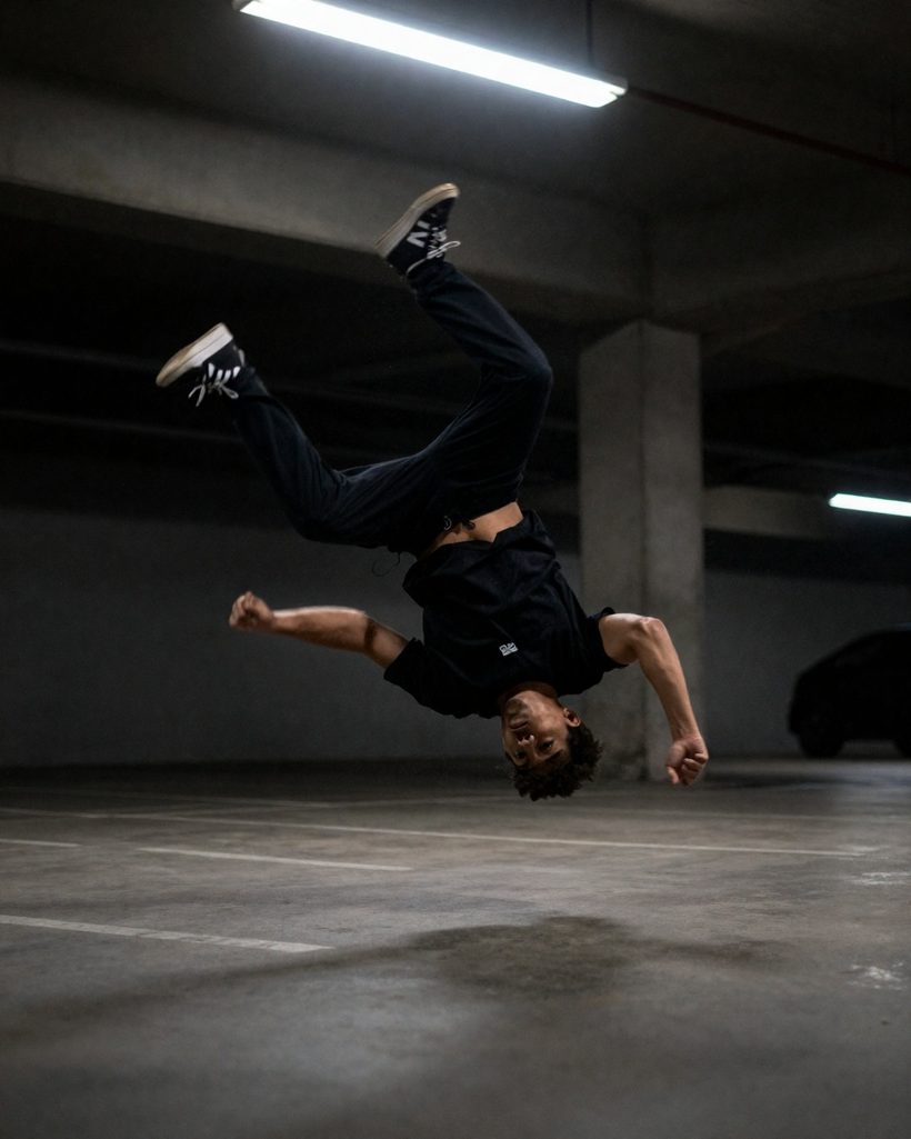 Street dancer upside down mid-move in a parking garage